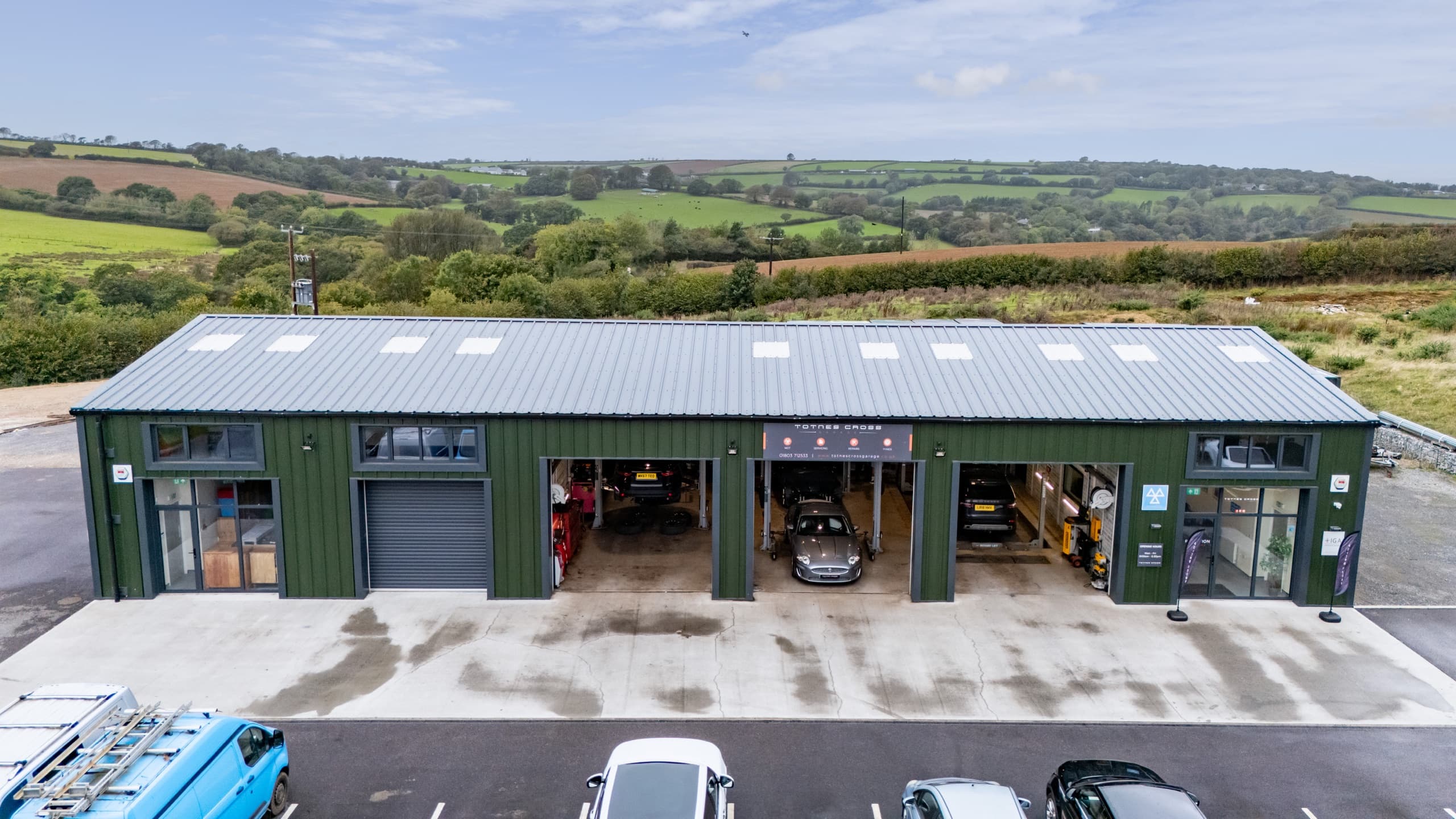 Aerial view of the Totnes Cross Garage workshop at Halwell, with open service bays and the South Hams countryside behind