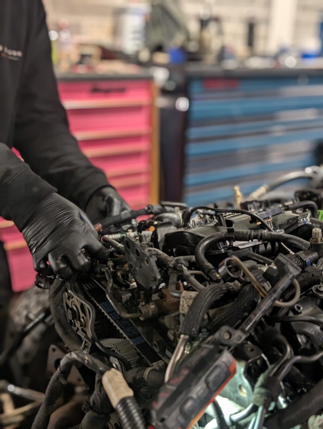 A technician in gloves working on an engine in the workshop